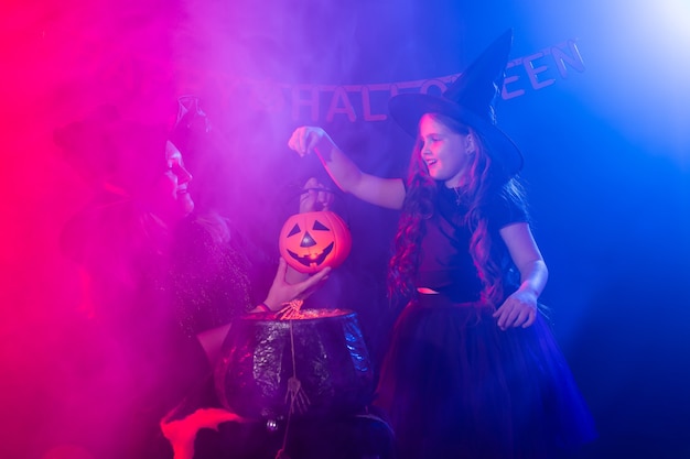 Criança engraçada menina e mulher em trajes de bruxas para o Halloween com a abóbora Jack.