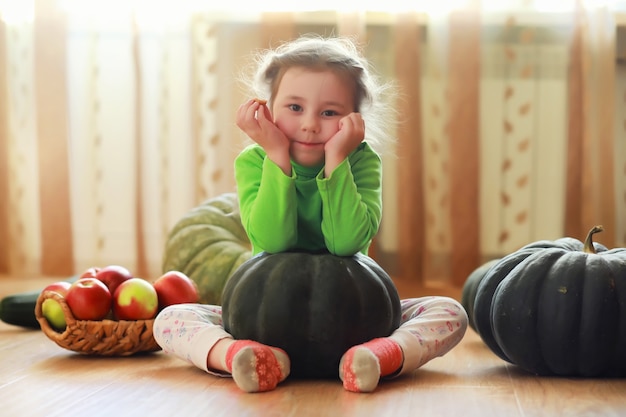 Criança escolhe uma abóbora no outono. Criança sentada na abóbora gigante. A abóbora é um vegetal tradicional usado nos feriados americanos - Halloween e Dia de Ação de Graças.