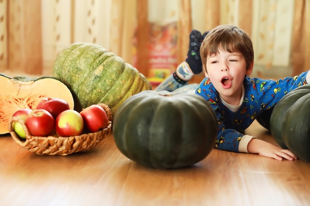 Criança escolhe uma abóbora no outono. Criança sentada na abóbora gigante. A abóbora é um vegetal tradicional usado nos feriados americanos - Halloween e Dia de Ação de Graças.