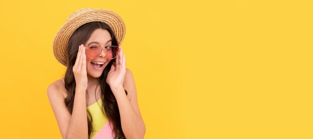 Foto criança espantada com chapéu de palha de verão e óculos tem cabelo encaracolado em fundo amarelo moda praia criança rosto horizontal cartaz adolescente menina isolado retrato banner com espaço de cópia