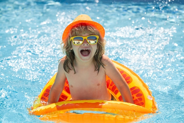 Criança espirrando na piscina nadar atividade esportiva aquática nas férias de verão com água para crianças