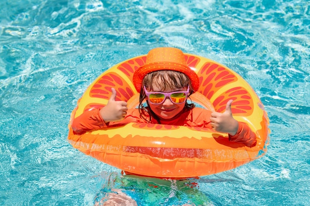 Criança espirrando na piscina nadar atividade esportiva aquática nas férias de verão com água para crianças