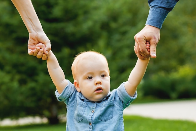 Criança está de mãos dadas com os pais