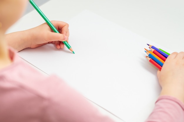 Criança está desenhando a lápis colorido