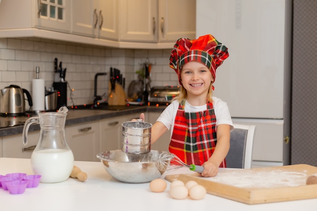 criança está preparando um jantar festivo criança peneirando a farinha em uma peneira conceito de inverno de ano novo