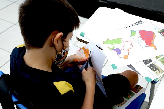 Criança estudando em uma sala de aula com livros e cadernos em cima da mesa