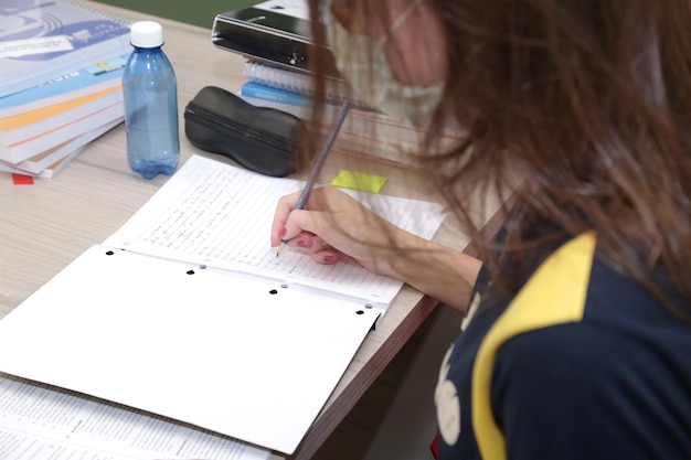 Criança estudando em uma sala de aula com livros e cadernos em cima da mesa