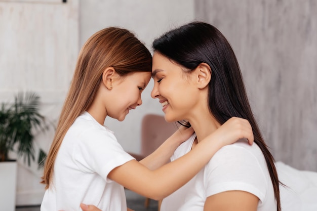 Foto criança excitada abraçando sua mãe enquanto está de pé perto cara a cara