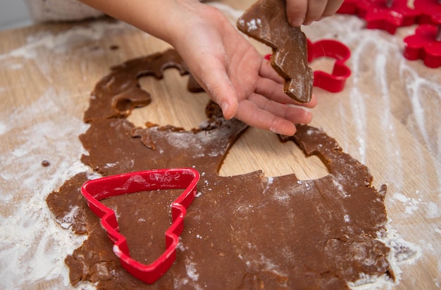 Criança faz biscoitos de Natal de massa de pão de gengibre e cortadores de biscoito. Conceito de cartão de Natal.
