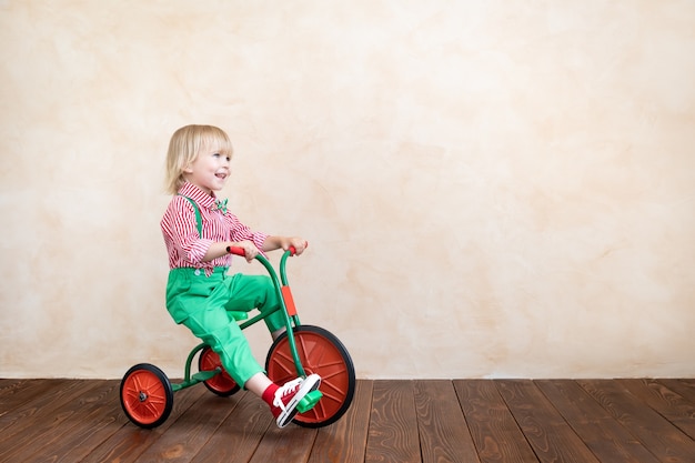 Criança feliz andando de triciclo vintage