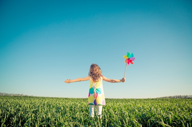 criança feliz ao ar livre contra o céu azul criança se divertindo no campo verde primavera liberdade e imaginação