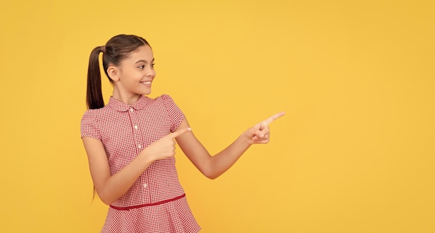 Criança feliz apontando o dedo no anúncio de espaço de cópia de fundo amarelo