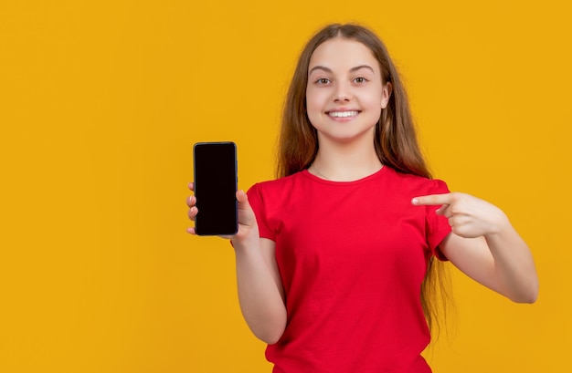 Foto criança feliz apontando o dedo no smartphone em fundo amarelo