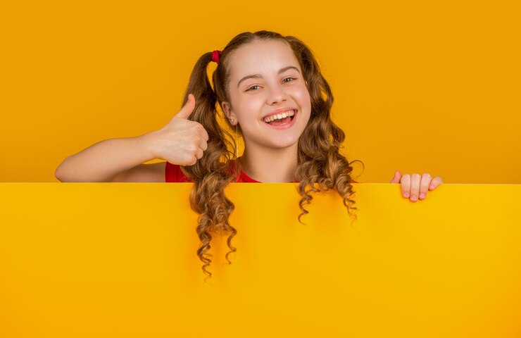 Foto criança feliz atrás de papel amarelo em branco com espaço de cópia para publicidade polegar u