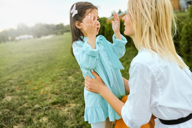 Criança feliz brincando com a jovem mãe ao ar livre Retrato de mulher alegre e seu filho fofo brincando no parque Mãe e filha compartilham amor Feliz Dia das Mães Maternidade e infância