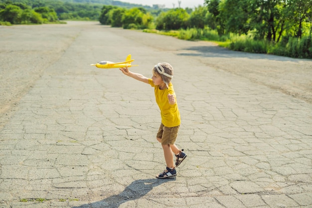 Criança feliz brincando com avião de brinquedo contra o antigo fundo da pista Viajando com o conceito de crianças