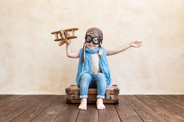 Criança feliz brincando com avião de madeira vintage.