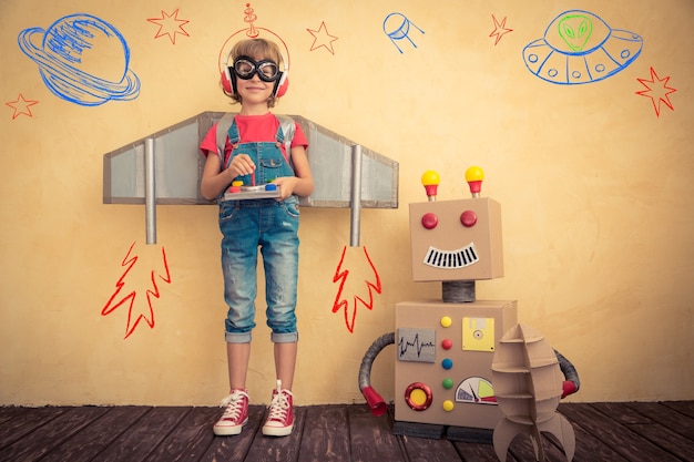 Criança feliz brincando com o robô de brinquedo em casa. Tecnologia de inovação e conceito de sucesso