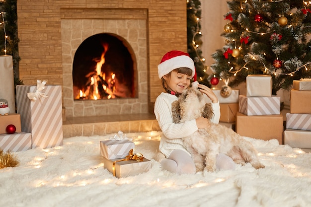 Criança feliz brincando com seu animal de estimação favorito em casa na véspera de Natal