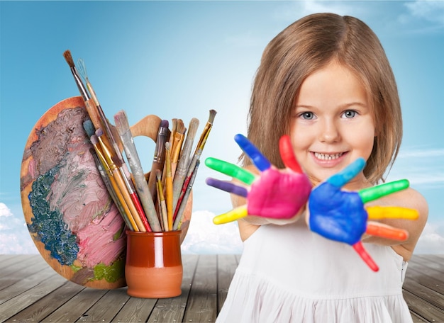 Criança feliz brincando com tintas nos dedos.