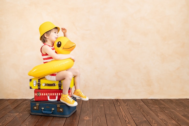 Criança feliz brincando em casa. criança sorridente, sonhando com as férias de verão e viagens. conceito de imaginação e liberdade