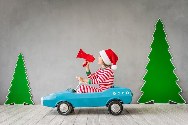 Criança feliz brincando em casa. Garoto engraçado na véspera de natal