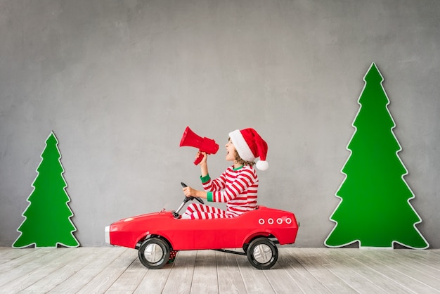 Criança feliz brincando em casa. Garoto engraçado na véspera de natal