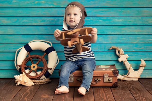 Criança feliz brincando em casa. Menino com avião de brinquedo