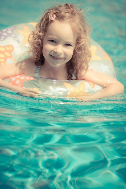 Criança feliz brincando na piscina Conceito de férias de verão