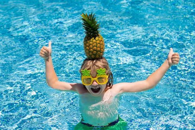 Criança feliz brincando na piscina Férias de verão para crianças Garotinho relaxando em uma piscina se divertindo durante as férias de verão Fruta de abacaxi engraçada para crianças