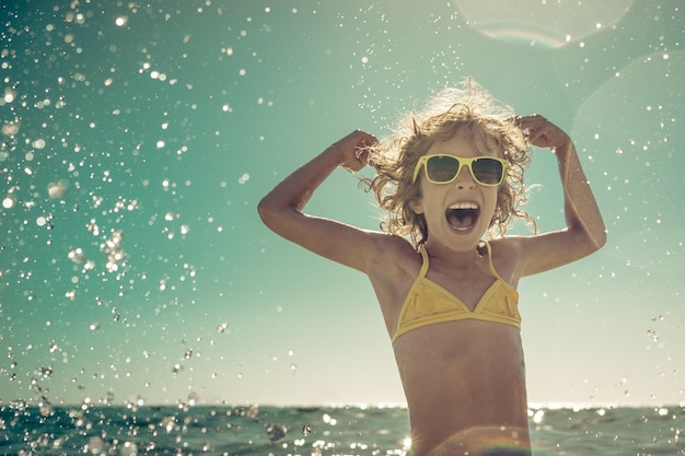 criança feliz brincando no mar