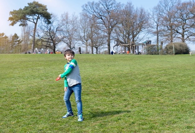 Criança feliz brincando no parque em um dia ensolarado de primavera