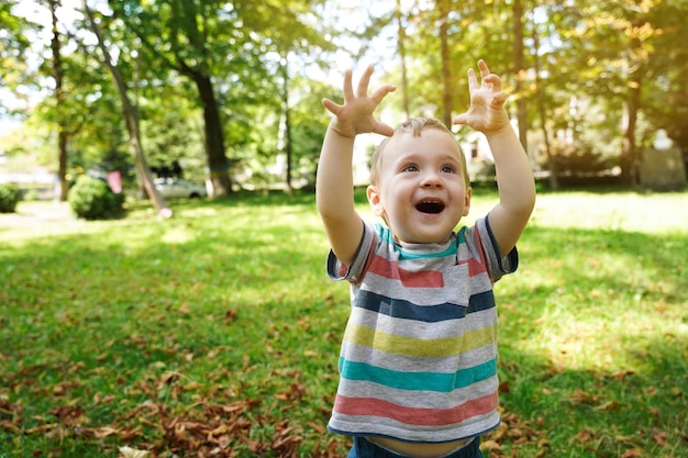 Criança feliz brincando no parque em um dia ensolarado garoto sorridente de um ano e meio ao ar livre infância alegre foco seletivo