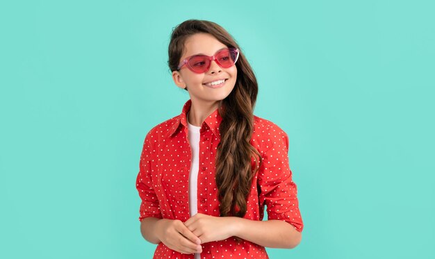 Criança feliz cabelo longo encaracolado em óculos de sol e camisa casual infância