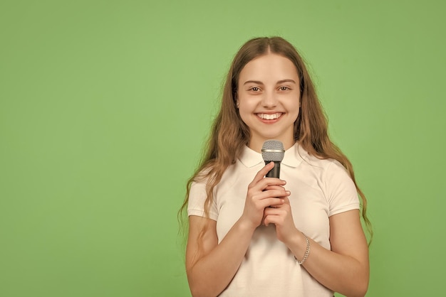 Criança feliz cantando no microfone em fundo verde com música de espaço de cópia