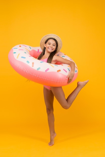 Criança feliz com anel de borracha atividade de férias de verão menina alegre vestindo maiô e chapéu de palha piscina e praia diversão infância felicidade ativa moda infantil pequena beleza