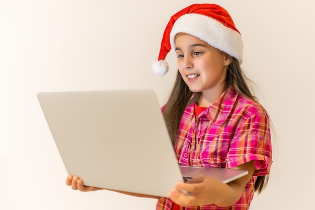 Criança feliz com chapéu de Papai Noel e computador portátil