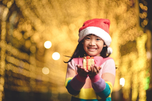 Criança feliz com chapéu de Papai Noel vermelho segurando os presentes de Natal. Época de Natal.