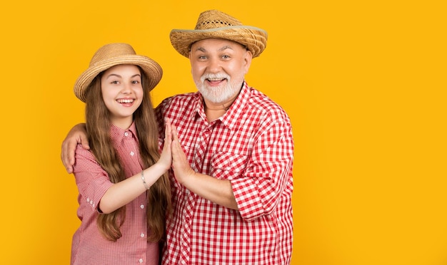 Criança feliz com o avô no chapéu de palha no fundo amarelo