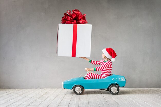 Criança feliz com o presente de Natal. Criança se divertindo em casa