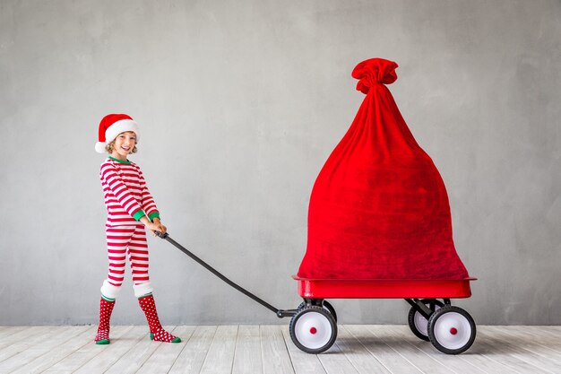 Criança feliz com o presente de Natal. Criança se divertindo em casa