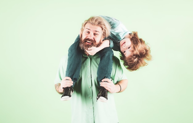 Criança feliz com pai pai e filho em fundo verde isolado Pai carregando criança nas costas Família se divertindo