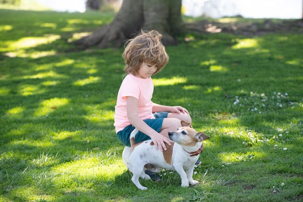 Criança feliz com retrato de cachorro crianças menino com animal de estimação brincando do lado de fora criança acariciando cachorro