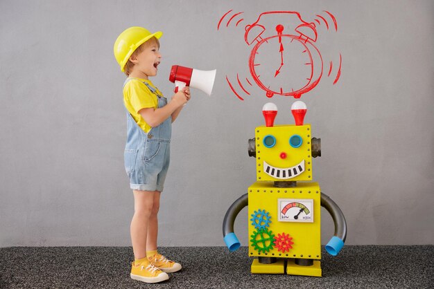 Criança feliz com robô. garoto engraçado jogando em casa. menino gritando no alto-falante. conceito de tecnologia de sucesso, criativo e inovação