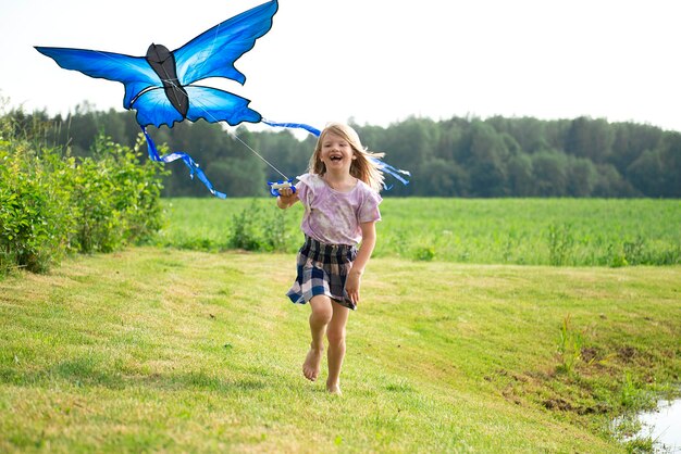 Criança feliz com uma borboleta azul correndo no prado na natureza de verão