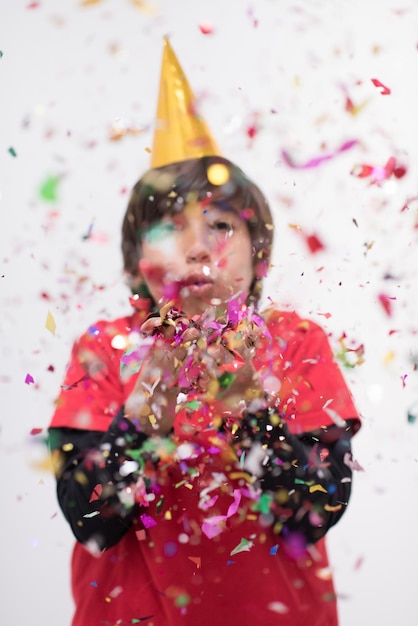 Criança feliz comemorando festa com confete soprando