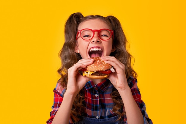 Foto criança feliz comendo hambúrguer fast food