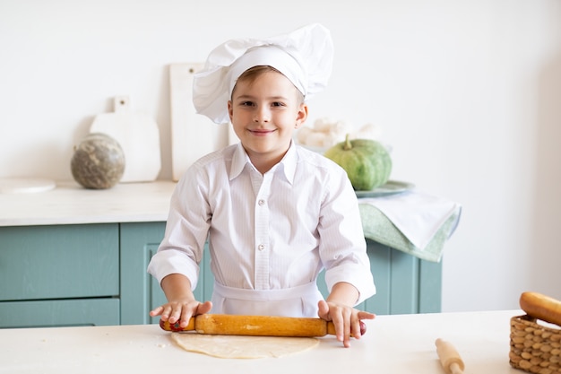 Criança feliz, cozinhando na cozinha usando toque