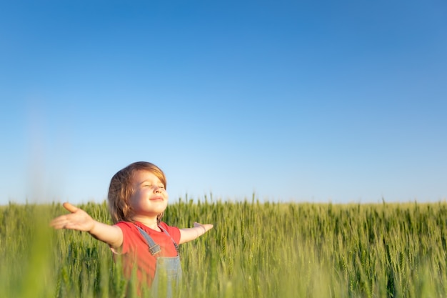 Criança feliz curtindo o sol ao ar livre em campo verde