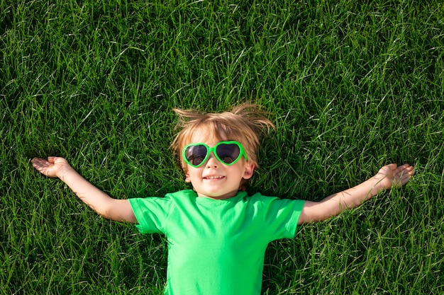 Criança feliz deitada na grama verde